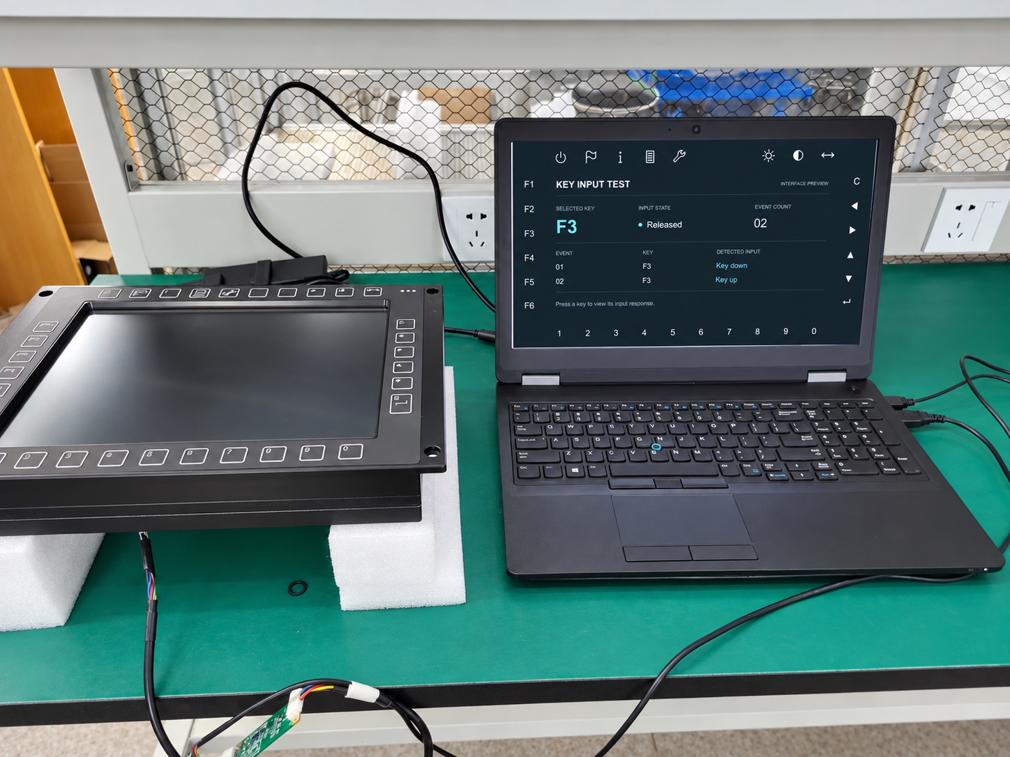 Industrial HMI keypad connected to a laptop for functional input testing